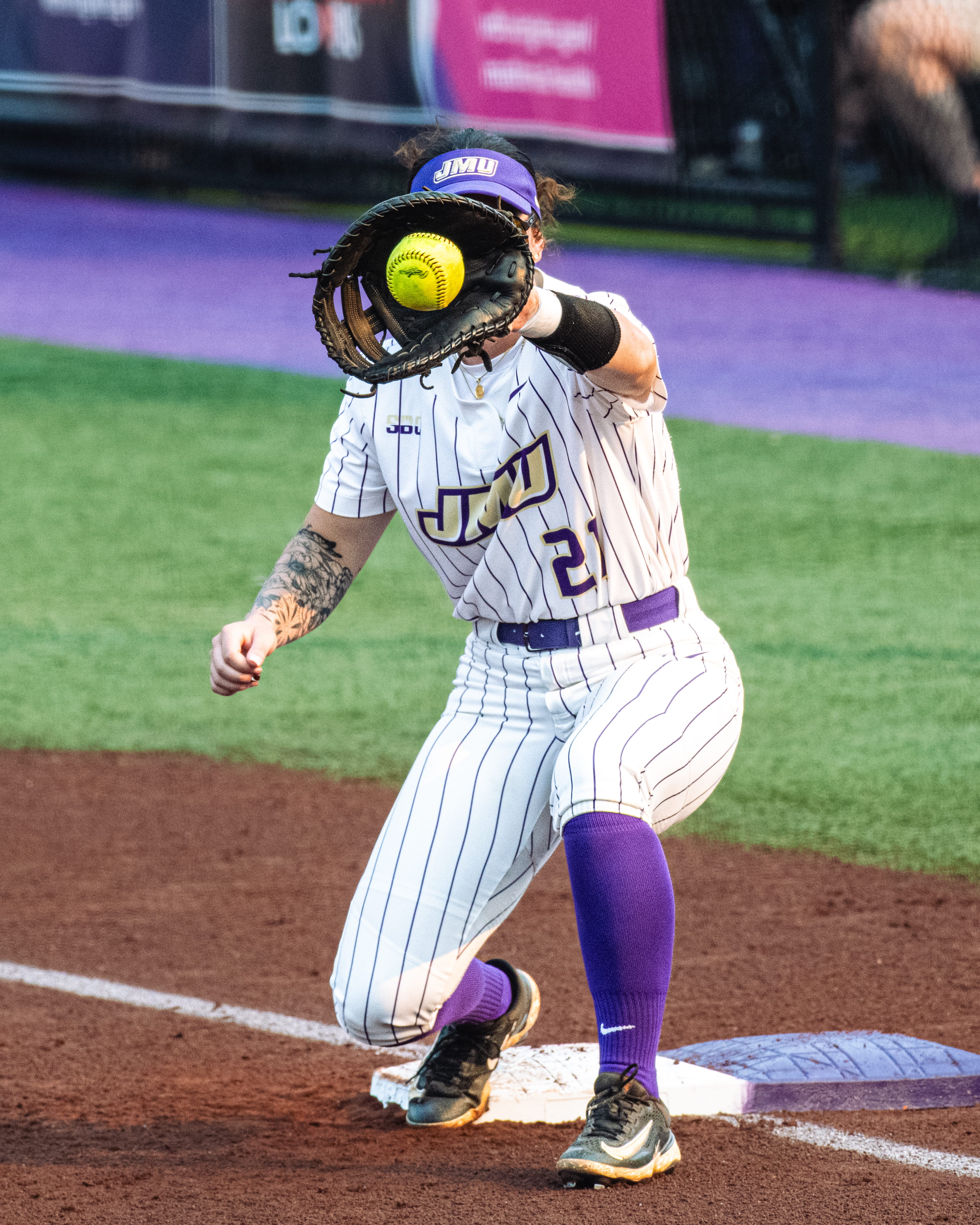 JMU softball player catching a bright yellow ball in her glove